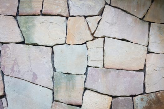Multi-colored and multi-sized, pale rocks wall grunge texture background.