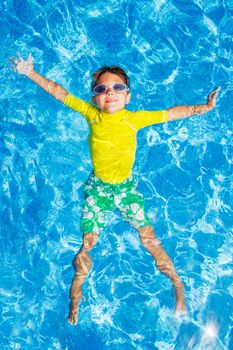 Cute happy little boy in goggles swimming and snorking in the swimming pool