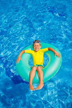 Cute little boy swims in a pool in an green life preserver