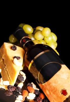 red wine bottle with grape and cheese on black