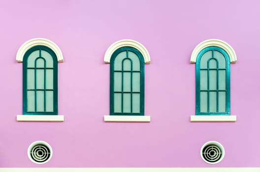 Three green arched windows on pink wall of the house in Italy retro style