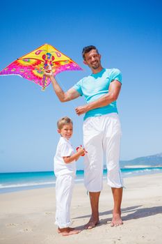 Summer vacation - Cute boy with his mother flying kite beach outdoor.