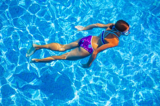 Cute happy young girl swimming and snorking in the swimming pool