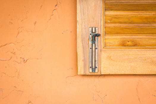 vintage window latch on a classic timber window panel, on orange grungy wall