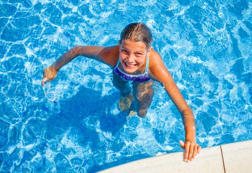 Cute happy young girl swimming and snorking in the swimming pool