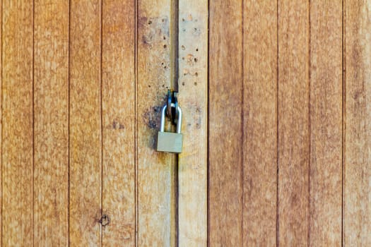 Old wooden doors are locked with a padlock, with copyspace
