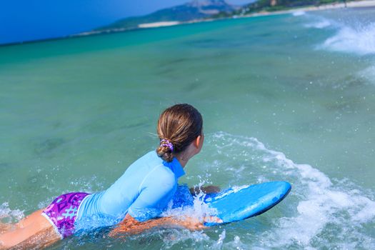 Teenage girl in blue has fun surfing