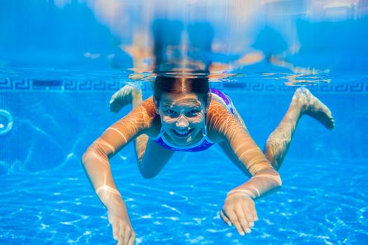 Underwater happy cute girl in swimming pool