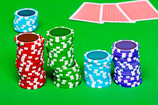 Stack of chips on the background of green the table. Cards in the background