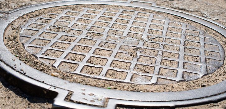 Metal manhole cover with checkered surface. Close up. 