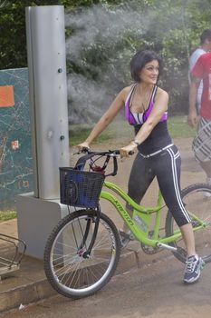 SAO PAULO, BRAZIL - FEBRUARY 01, 2015: An unidentified biker girl refresh at the water spray in the Ibirapuera Park at Sao Paulo Brazil.
