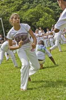 SAO PAULO, BRAZIL - FEBRUARY 01, 2015: An unidentified girl fights capoeira in a circle of people with traditional samba music on the grass of Ibirapuera Park at Sao Paulo Brazil.