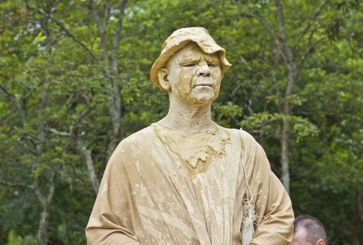 SAO PAULO, BRAZIL - FEBRUARY 01, 2015: An unidentified man executing a popular living statue performance covered with mud in one street of Ibirapuera Park at Sao Paulo Brazil.