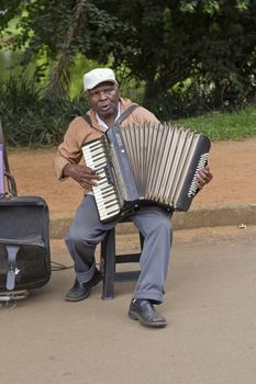 SAO PAULO, BRAZIL - FEBRUARY 01, 2015: An unidentified street musician singing and playing one old accordion in the Ibirapuera Park at Sao Paulo Brazil.