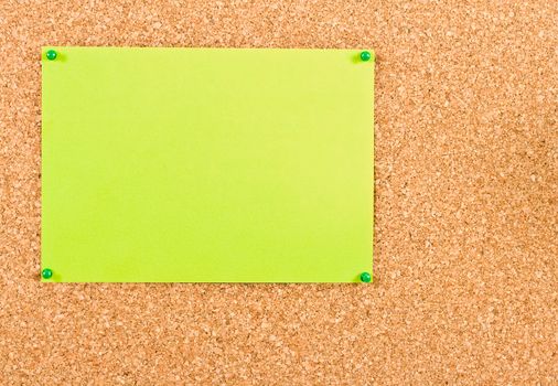 Green sheet of paper attached to corkboard buttons