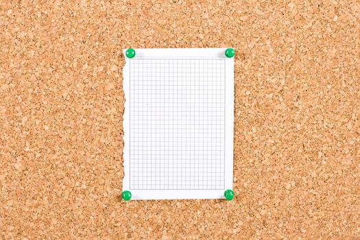 Photo of a piece of squared paper taken out of a notebook, the paper is pinned to a cork board, the photo is ideal as background for informations.
