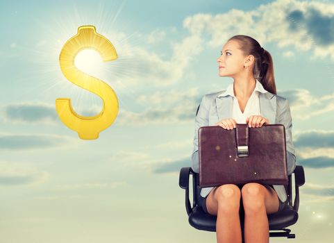 Businesswoman sitting on office chair, holding briefcase on her knees, looking at golden dollar sign in the air, against blue sky with clouds