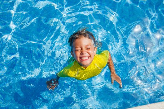 Cute happy little boy swimming and snorking in the swimming pool