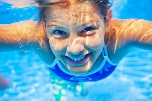 Close-up portrait of underwater happy cute girl in swimming pool