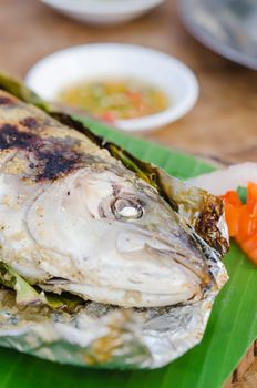 Grilled fish on green banana leaf with herbs
