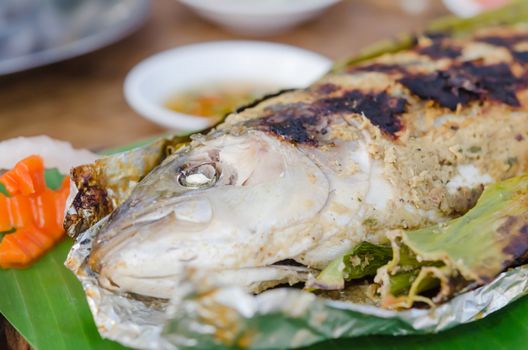 Grilled fish on green banana leaf with herbs