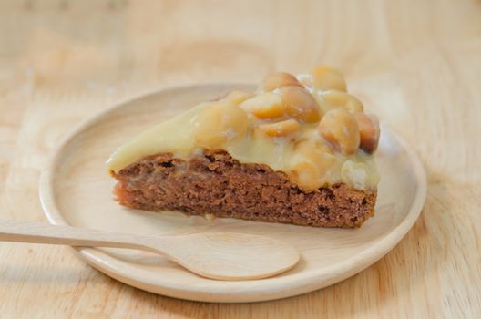 Piece of chocolate macadamia cake on wooden plate
