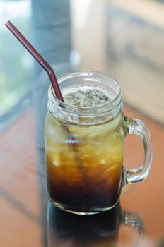 A glass of black iced coffee with drinking Straw