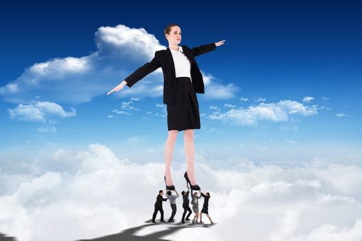 Business people supporting boss against bright blue sky with clouds