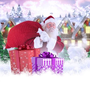 Santa carries his red bag and smiles against row of house with snow on them