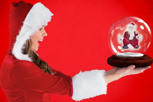 Composite image of sexy santa girl holding snow globe against red background