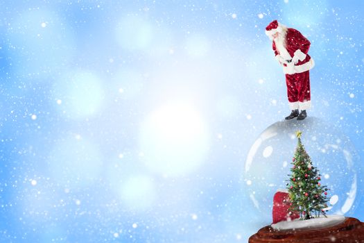 Santa standing on snow globe against blue abstract light spot design