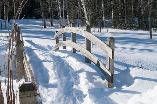 Footbridge in the winter with a path in the snow