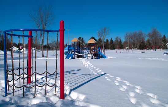 Track in the snow to playground equipment in the winter