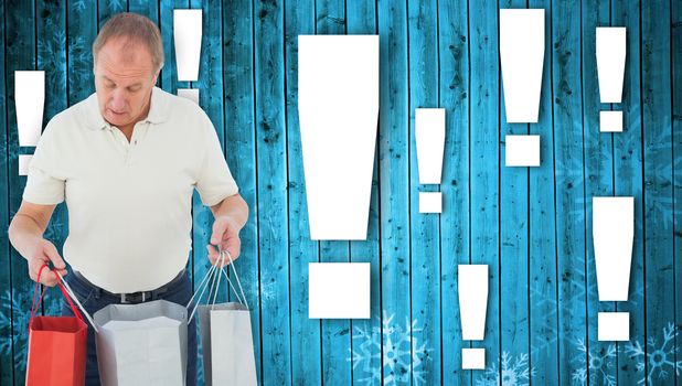 Man looking in shopping bags against snowflake pattern on blue planks