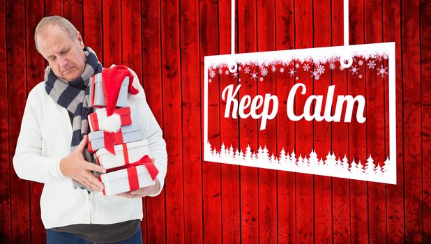 Festive man holding christmas gifts against red wooden planks background