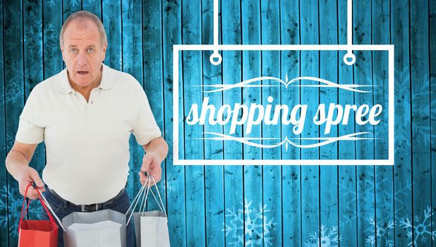 Shocked man holding shopping bags against snowflake pattern on blue planks