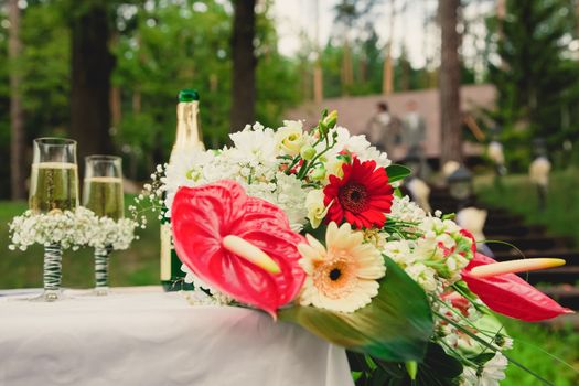 Wedding ceremony in a beautiful garden. The bride's bouquet. Champagne and two glasses