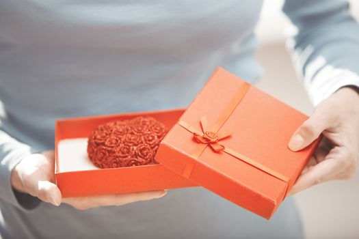 Woman holding gift box with cake in form of heart