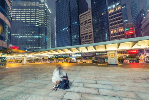 HONG KONG - APRIL 19, 2014: Unknown female photographer takes pictures of night city skyline. The city is a famous destination for worldwide photographers.