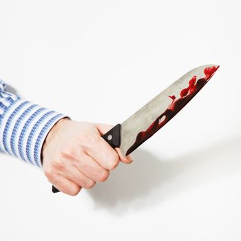 The hand  is holding the knife with blood on a white background.