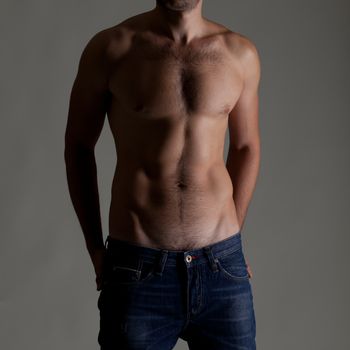 Sexy muscular naked man in jeans on dark background