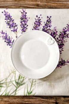 Empty plate laid on vintage wooden dining table with colorful tablecloth