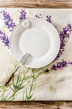 Plate and fork on vintage wooden dining table with colorful tablecloth