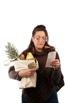 Middle aged woman carefully examining her register receipt reviewing her grocery shopping bill.