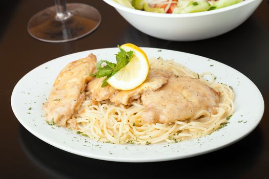 Chicken francaise or francese plated with pasta with salad in the background.