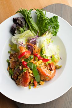 Thai jumbo shrimp salad on a round white plate. Shallow depth of field.