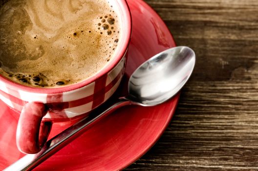 Detail view of coffee in red cup on wooden vintage table