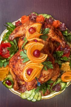 Whole roasted chicken with vegetables and fruits on wooden table