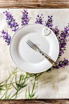 Plate and fork on vintage wooden dining table with colorful tablecloth