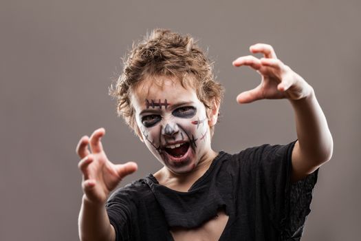 Halloween or horror concept - screaming walking dead zombie child boy reaching hand